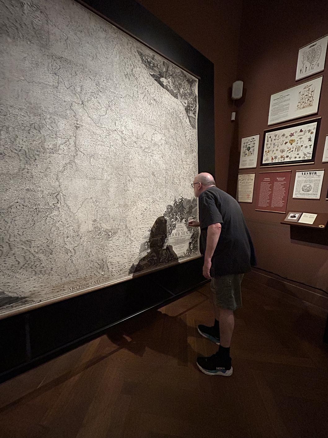 A huge monochrome map of Bohemia, six feet on a side, with elaborately decorative corner pieces, mounted on a wall, being closely examined by myself